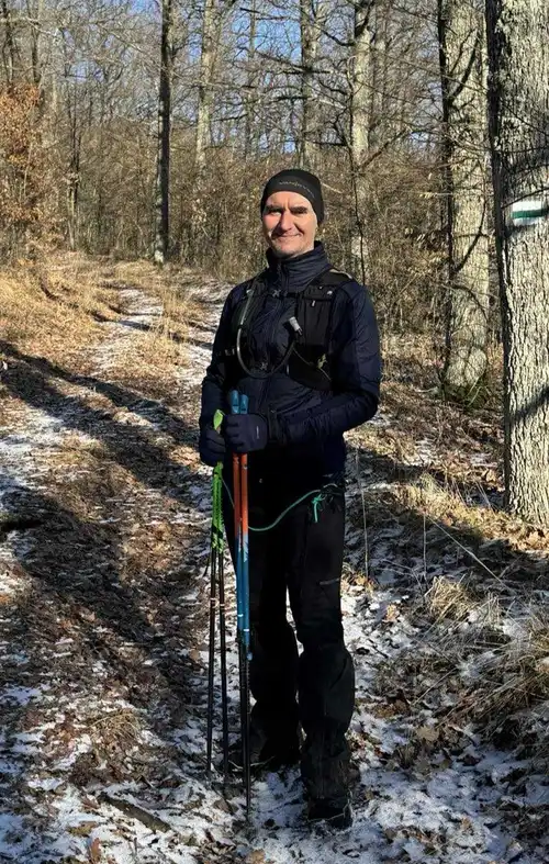 Lélekélettan mentor program alapítója, Váczy József terepfutó felszerelésben és nordic botokkal egy erdei úton, szemléltetve a biológiai erőforrások teljes helyreállítását és az aktív életörömöt.